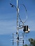 Väderstationen består av vindsnurran uppe till vänster och den svart/vita burken till höger (regnmätare, temp/daggpunkt, sol, UV). Den runda saken är en loopantenn för MF/HF, Wellbrook ALA1530LNP. Underst sitter en TV-antenn, som är riktad mot Algutsrum. (2017-08-08 Antennmast_0038)